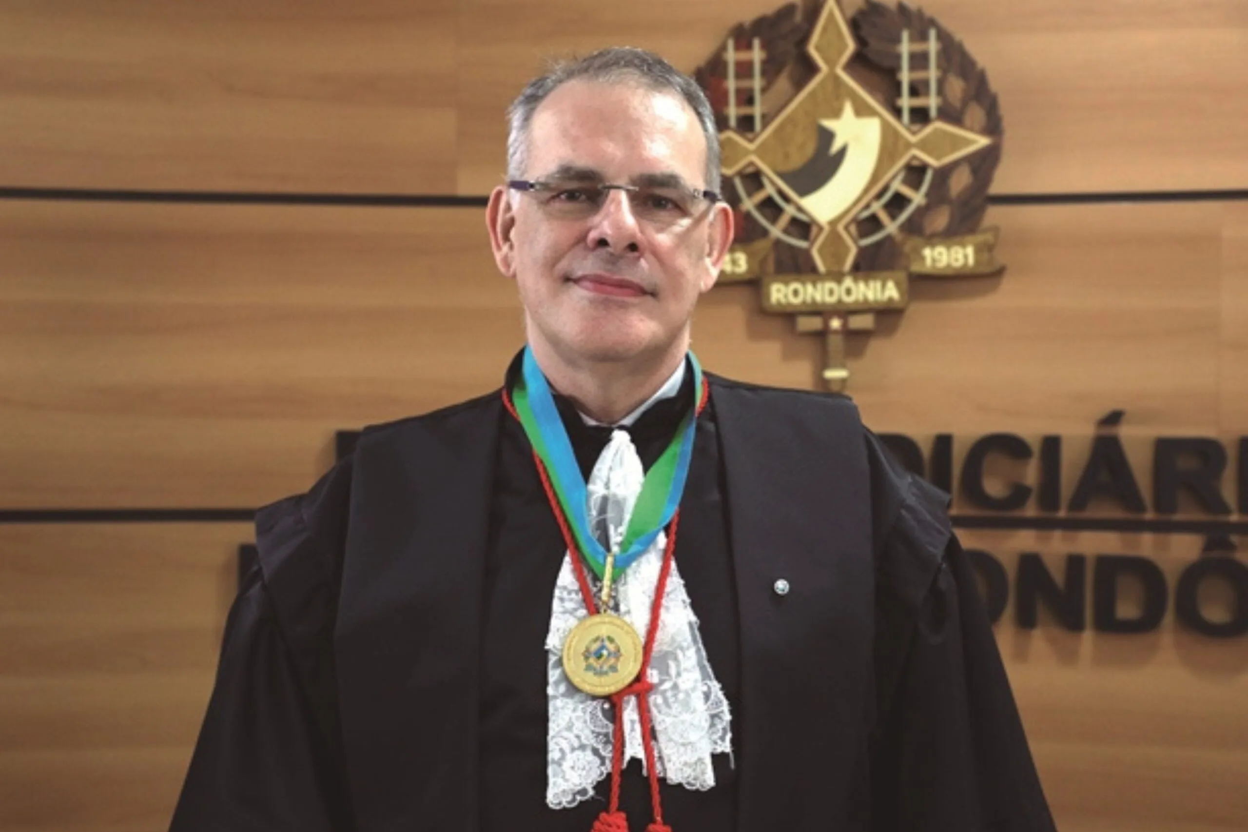 Homem branco trajado com roupaz de juiz posado para foto 