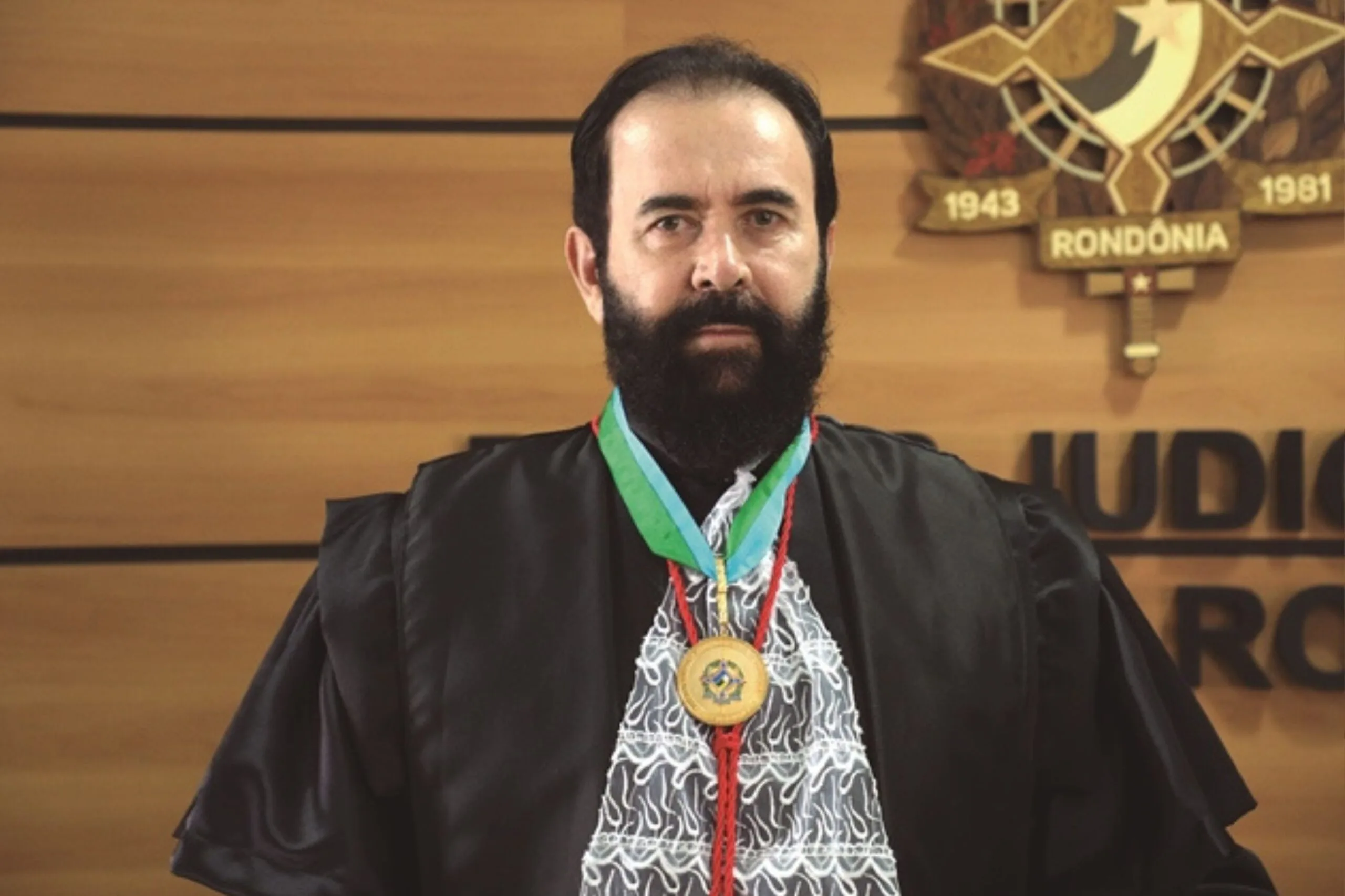 Homem branco trajado com roupaz de juiz posado para foto 