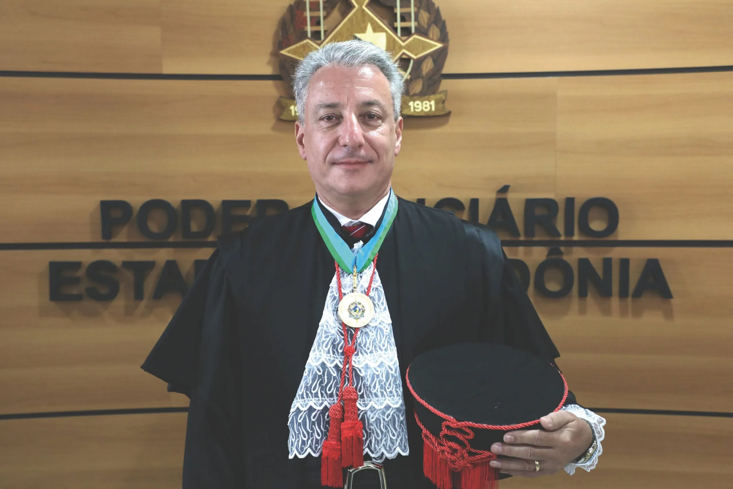 Homem branco trajado com roupaz de juiz posado para foto 