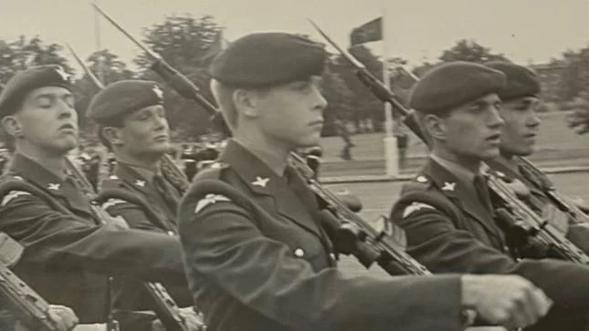 Imagem em preto e branco mostra jovens integrantes do Regimento de Paraquedistas marchando em um pátio de formatura. Os soldados carregam fuzis SA80 com baionetas fixadas